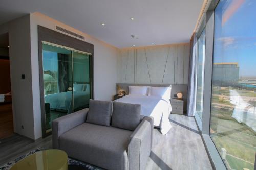 Views Hotel & Residences في King Abdullah Economic City: غرفة نوم بسرير واريكة ونافذة