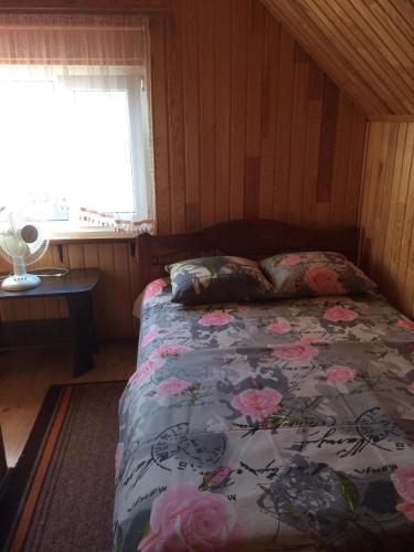 um quarto com uma cama com flores cor-de-rosa em садиба Подвір'ячко em Szack