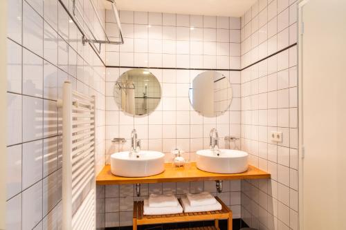 two sinks in a white tiled bathroom with mirrors at Villa 1913 in Bergen