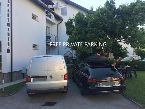 a white van and a black car parked next to a building at Apartman SONAS 2 with free private parking in Karlovac