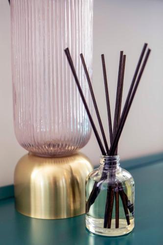 a glass vase with sticks in it next to a lamp at Beautiful, modern apartment in Hope Place Bath, 1 Bedroom Luxury City Centre Apartment with Beautiful City Views, a stones throw from The Royal Crescent in Bath in Bath