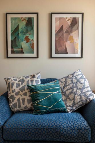 a blue couch with pillows in a living room at Beautiful, modern apartment in Hope Place Bath, 1 Bedroom Luxury City Centre Apartment with Beautiful City Views, a stones throw from The Royal Crescent in Bath in Bath
