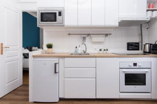 une cuisine blanche avec un évier et un micro-ondes dans l'établissement Cabourg Cosy chic Cabourg hyper-centre 4 pers, 2 bedrooms , 2 sdb, terrasse, wifi, à Cabourg