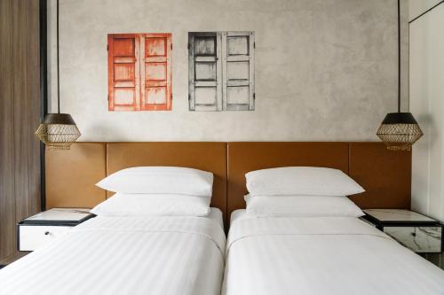two beds in a room with two windows at JEN Singapore Tanglin by Shangri-La in Singapore