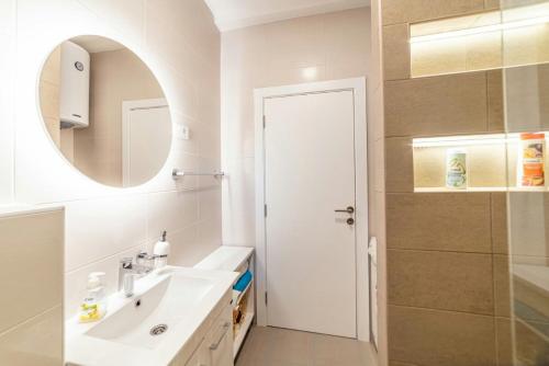 biała łazienka z umywalką i lustrem w obiekcie Apartman Danube lux w Nowym Sadzie