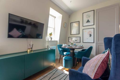 uma sala de estar com uma mesa e cadeiras azuis em Beautiful, modern apartment in Hope Place Bath, 1 Bedroom Luxury City Centre Apartment with Beautiful City Views, a stones throw from The Royal Crescent in Bath em Bath