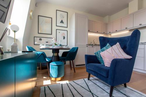 a living room with a blue chair and a table at Beautiful, modern apartment in Hope Place Bath, 1 Bedroom Luxury City Centre Apartment with Beautiful City Views, a stones throw from The Royal Crescent in Bath in Bath