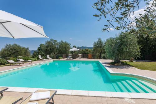 a swimming pool with chairs and an umbrella at Villa Rachele in Monte Amiata