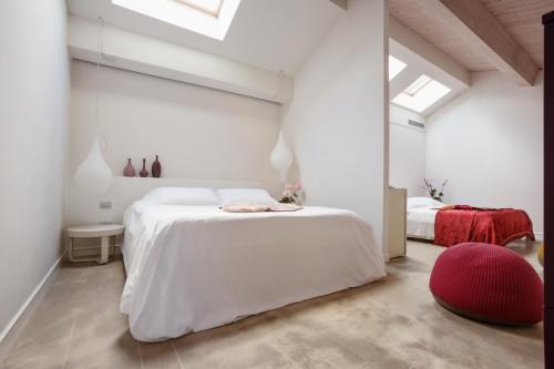 a white bedroom with a white bed and a red chair at Shalai in Linguaglossa