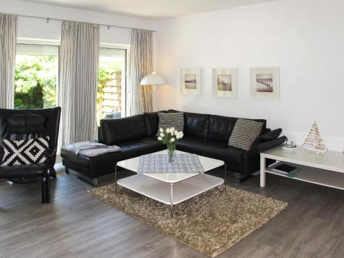 a living room with a black couch and a table at Holiday Home Am Walde by Interhome in Lubmin