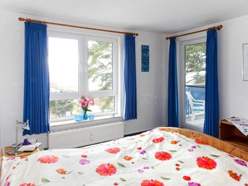 1 Schlafzimmer mit einem Bett und 2 Fenstern mit blauen Vorhängen in der Unterkunft Apartment Blaumuschel - LUB101 by Interhome in Lubmin