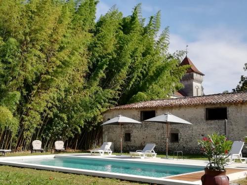 einen Pool mit Stühlen und Sonnenschirmen neben einem Gebäude in der Unterkunft Château des Salles in Saint-Fort-sur-Gironde