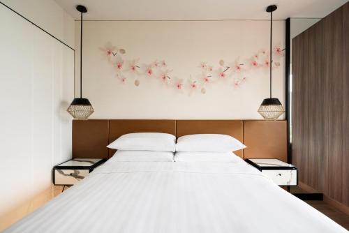 a bedroom with a large white bed with flowers on the wall at JEN Singapore Tanglin by Shangri-La in Singapore