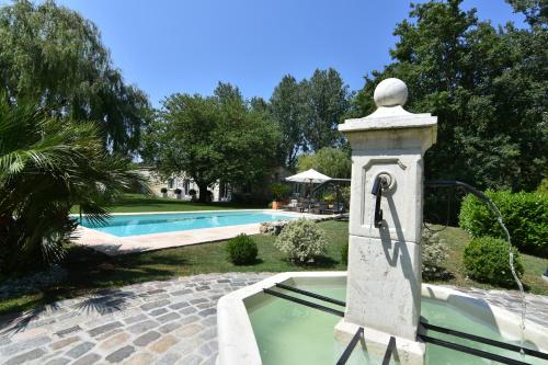 uma fonte de água junto a uma piscina em Chambres d'hôtes Domaine de Ginouilhac em Le Taillan-Médoc