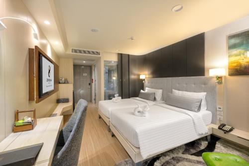 sypialnia z dużym białym łóżkiem i biurkiem w obiekcie Zenseana Resort & Spa - SHA Plus w Patong Beach