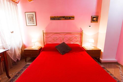 a red bed in a room with two lamps at Eden Lilli B&B in La Pieve