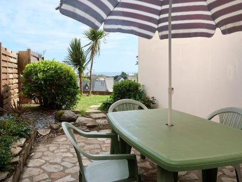 a green table and chairs with an umbrella on a patio at Holiday Home Tal ar Mor by Interhome in Le Pouldu