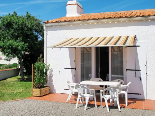 una casa blanca con mesa y sillas bajo un toldo en Holiday Home Le Maupas by Interhome, en La Tranche-sur-Mer