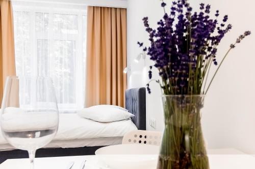 a room with a bed and a vase with purple flowers at Apartments Daina in Jūrmala