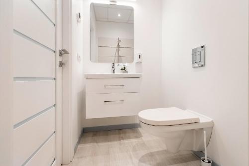 a white bathroom with a toilet and a sink at Apartments Daina in Jūrmala