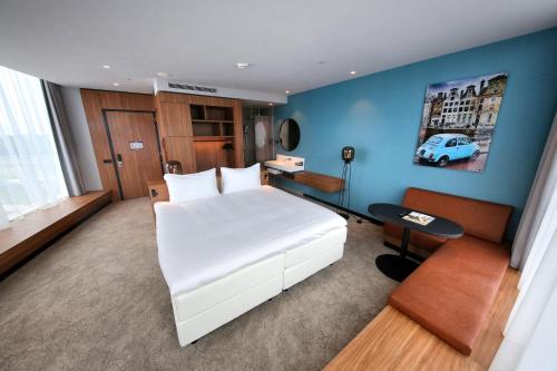 a bedroom with a white bed and a blue wall at Van der Valk Hotel Amsterdam Zuidas -Rai in Amsterdam