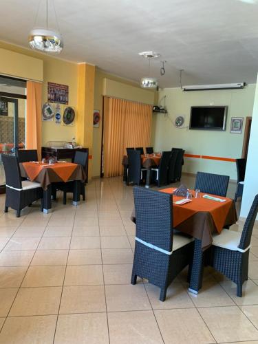 a dining room with tables and chairs and a tv at Stanza vacanza lo stadio in Sibari