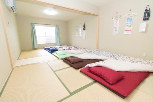 Yadocafe Chelsea's Rainbow B&B في أوساكا: غرفة مع صف من الوسائد على الأرض