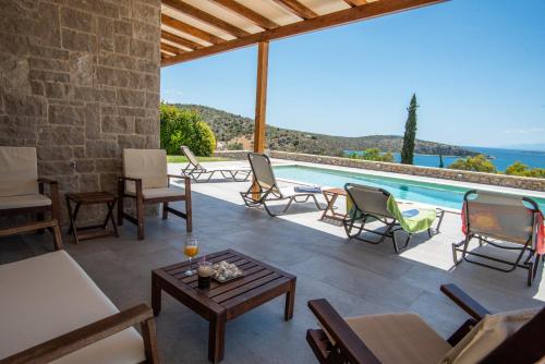 un patio con piscina, sillas y mesa en Lefka's Villas, en Vivari