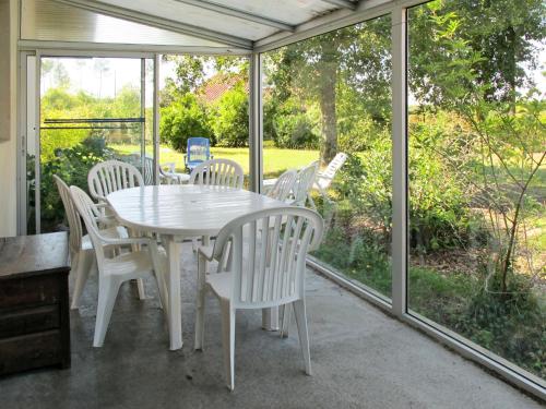 a white table and chairs on a screened in porch at Holiday Home Cherte by Interhome in Uza