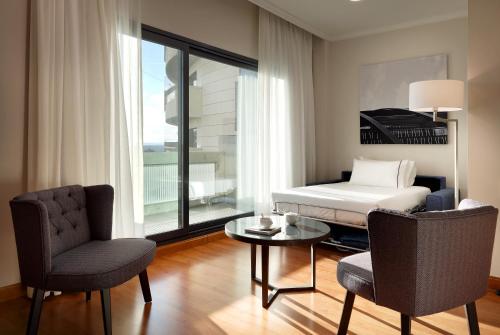 a bedroom with a bed and a table and chairs at Eurostars Madrid Foro in Tres Cantos
