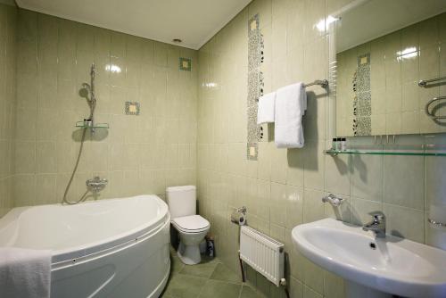 La salle de bains est pourvue de toilettes blanches et d'un lavabo. dans l'établissement Hotel Usengi, à Elbrouz