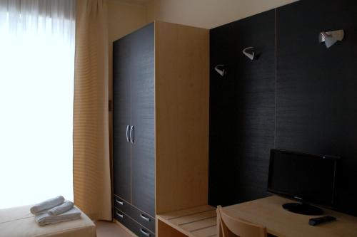 a bedroom with a bed and a desk with a television at Hotel Arno in Rimini