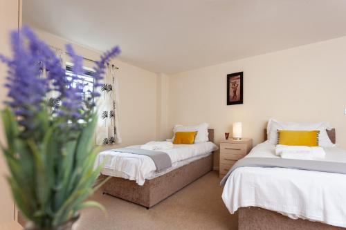 a bedroom with two beds and a vase of flowers at Oakstays Newcastle Gem in Newcastle upon Tyne