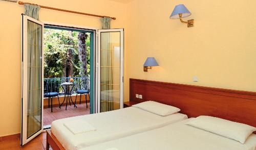 um quarto com 2 camas e uma porta de vidro deslizante em Poseidon Apartments em Agios Gordios