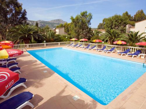 a pool with chairs and umbrellas at a hotel at Apartment Thalassa-1 by Interhome in Calvi