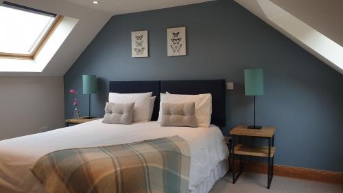 1 dormitorio con 1 cama grande con sábanas y almohadas blancas en Old Farm Holiday Cottages - Scottish Borders, en Chirnside