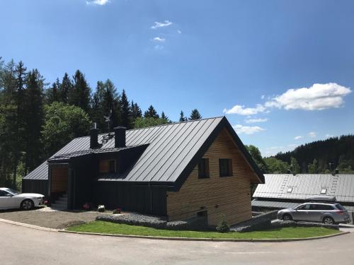 a house with a black roof and cars parked at Apartmany Slunecnice in Cerny Dul