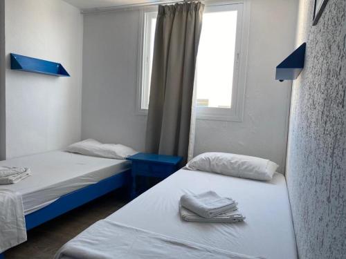 due letti in una piccola stanza con una finestra di Gecko Blue, Es Pujols ET - 75 PL a Es Pujols