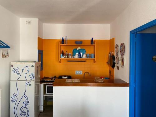 una cucina con frigorifero bianco e parete arancione di Gecko Blue, Es Pujols ET - 75 PL a Es Pujols