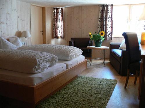 ein Schlafzimmer mit einem Bett und einem Stuhl sowie einer Vase aus Blumen in der Unterkunft Gasthaus Engel in Bezau