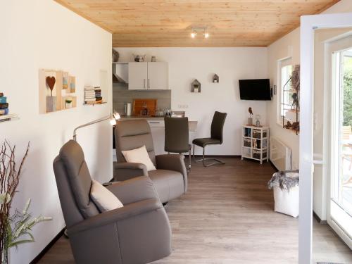a living room with a couch and chairs and a kitchen at Holiday Home Caro by Interhome in Kirburg