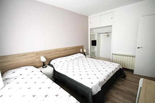 2 camas en un dormitorio con paredes blancas y suelo de madera en Villa Paradis, en Miami Platja