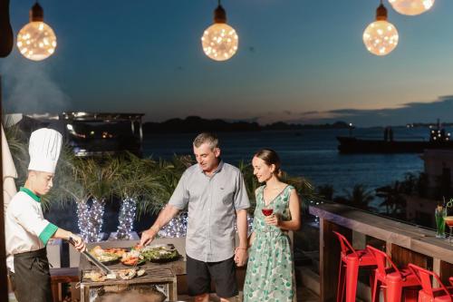 a man and a woman standing next to a table with food at Deja Vu House Ha Long in Ha Long