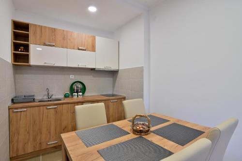 a kitchen with a wooden table with chairs and a sink at Apartment White Bear in Zlatibor