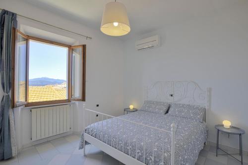 a white bedroom with a bed and a window at Casa il tramonto in Capoliveri