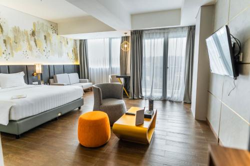 a hotel room with a bed and a chair at Nemuru Grand Bhuvana Ciawi in Bogor