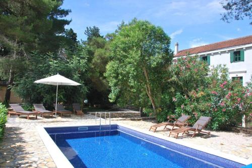 a swimming pool with chairs and an umbrella next to a house at Private luxury Villa del Mar on Solta for up to 10 persons, heated pool, free parking, next to sea! FREE Kajak & Mountainbikes, GREAT living area & privacy! in Rogač