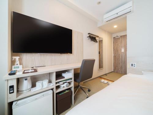a hotel room with a flat screen tv on a wall at Super Hotel Tokyo JR Kamata Nishiguchi in Tokyo