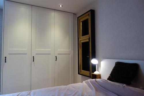 a bedroom with white cabinets and a bed and a mirror at Gîtes le second à Spa (gîte de 2 et de 5 personnes) in Spa