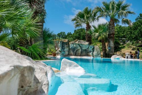 a swimming pool in a resort with palm trees at Agriturismo Zio Cristoforo in Casal Velino